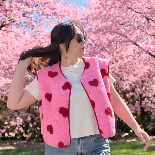 gilet sans manche rose et rouge avec petits cœurs porté sur un mannequin en extérieur