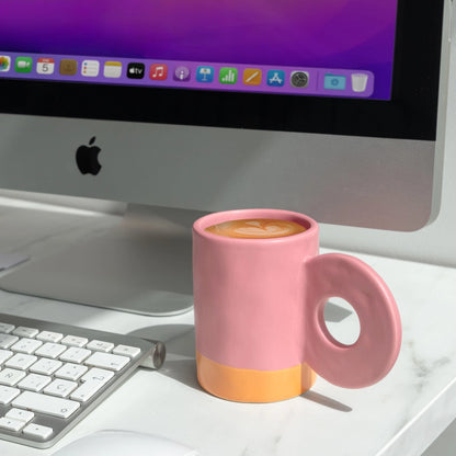 Mug bicolore en céramique rose posé sur un bureau